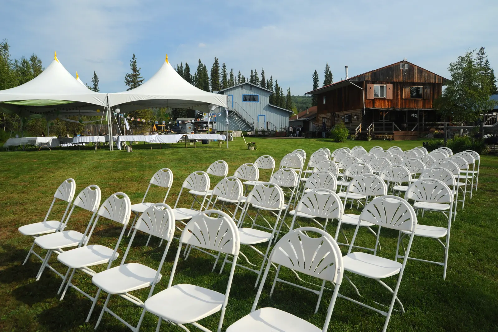 White folding chairs and rectangular tables with white tablecloths set up for an outdoor birthday party in El Paso, TX with colorful balloon decorations — Sweet n' Sassy Creations party furniture rental